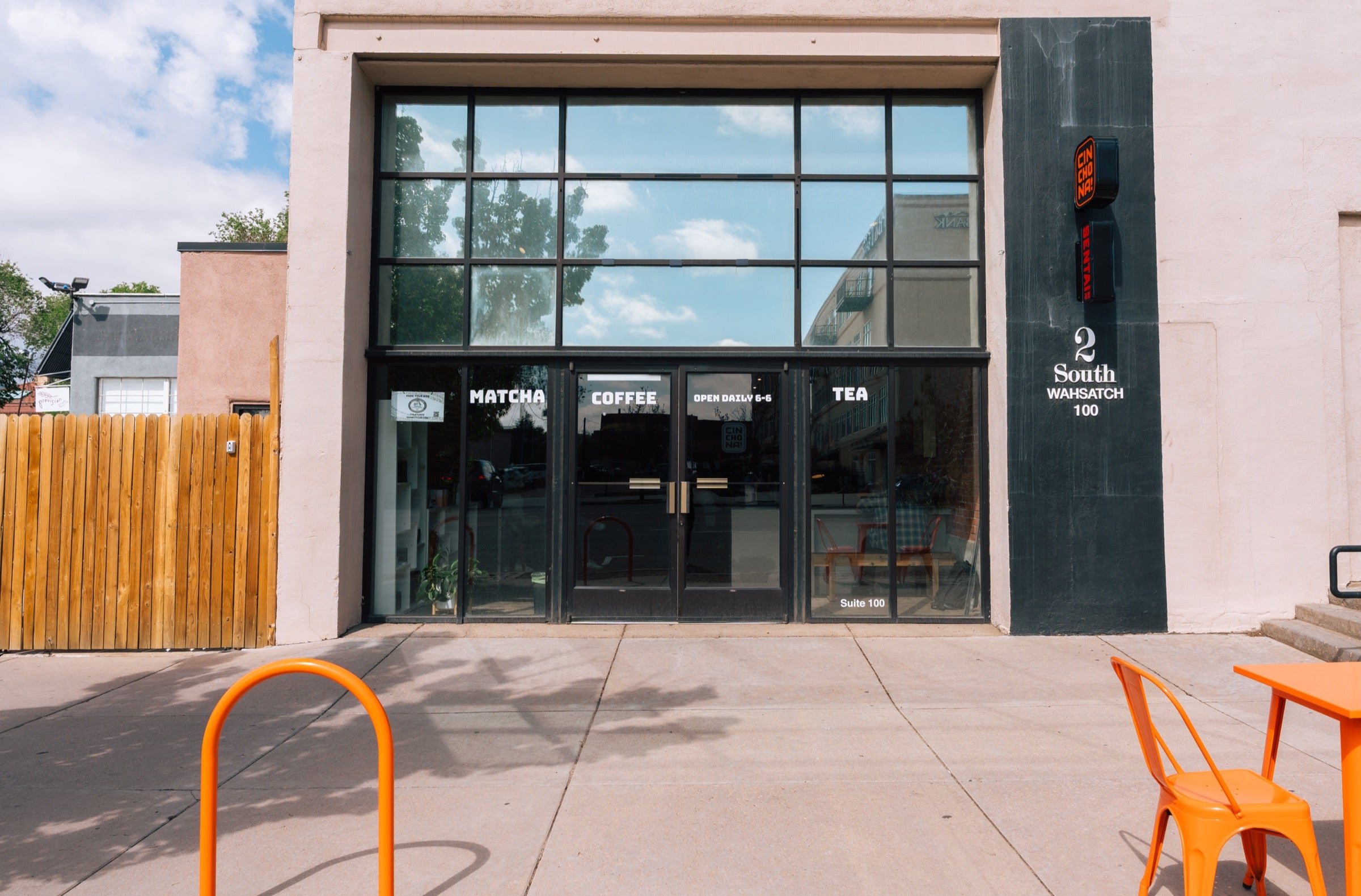 Cinchona storefront: black frontage, tall windows, orange chairs